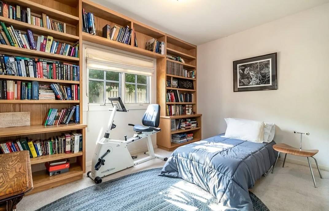 Floor-to-ceiling wood bookcases built around a window, full of books