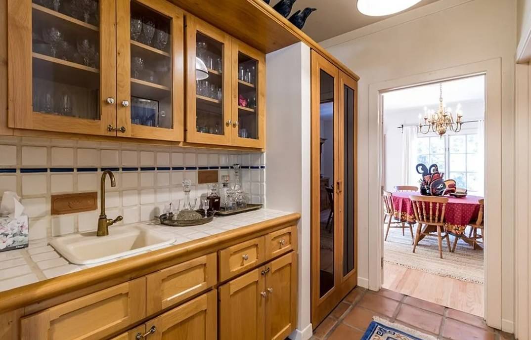 A butler’s pantry with glass-fronted wood cabinets, a small sink and drawers