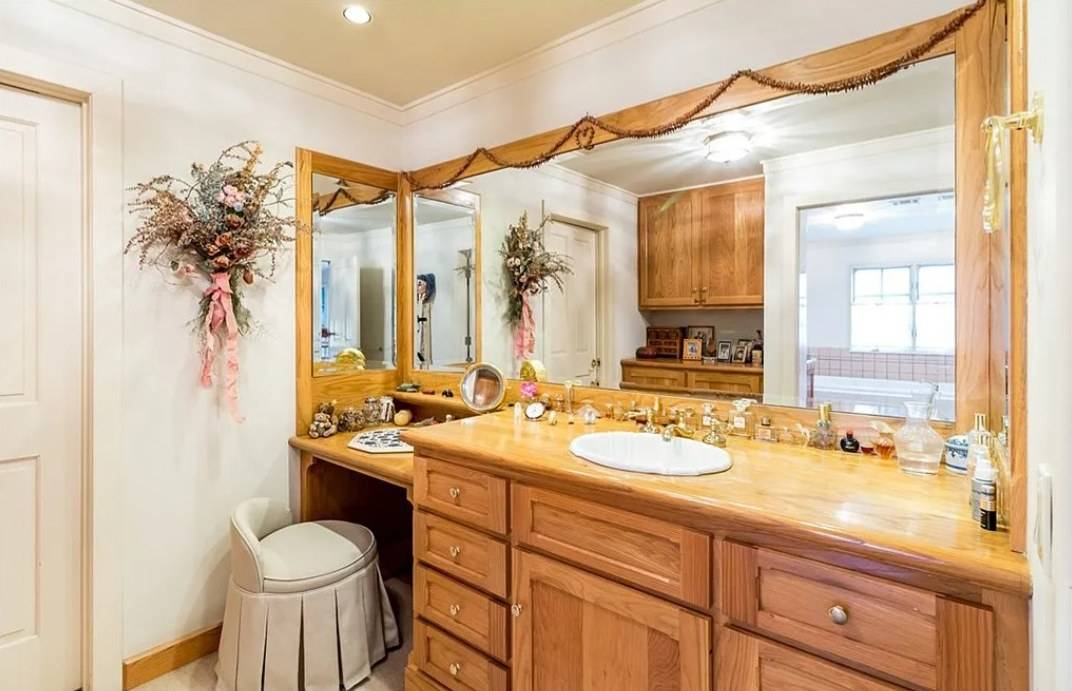 A long wood bath vanity with drawers and a dressing table section under a wide mirror