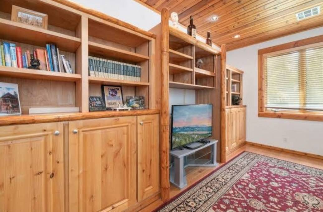 A wall of knotty wood bookcases and base cabinets fitted between peeled log posts