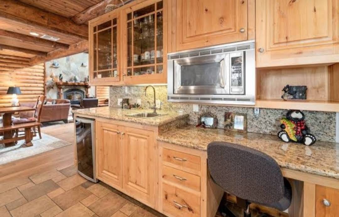 Knotty wood cabinets with glass-fronted doors above a granite bar and a built-in desk
