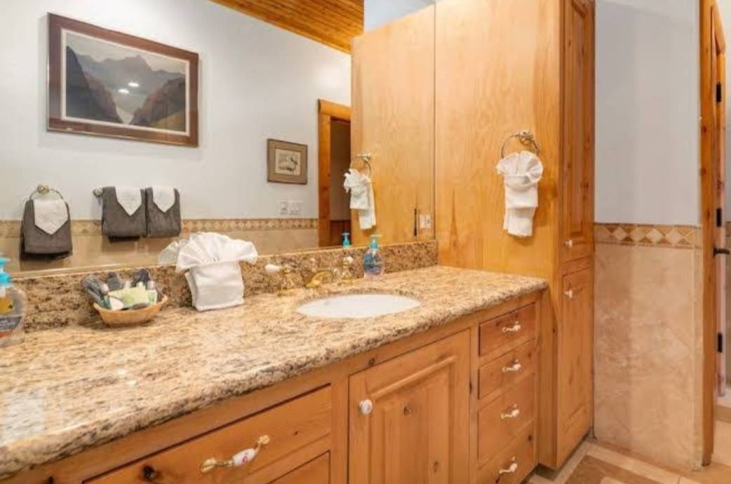 A knotty wood bath vanity with drawers and a tall linen tower beside it