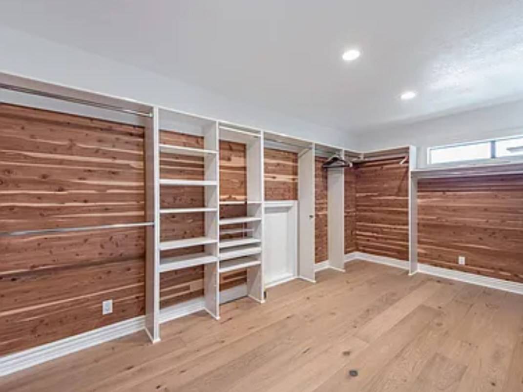 A walk-in closet lined in cedar boards with white shelf towers and hanging rods