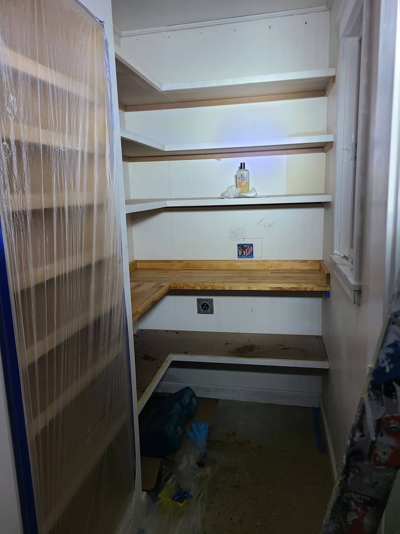 Painted white pantry shelves wrapping two walls