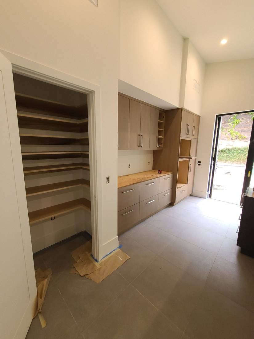 Light oak flat-panel cabinets with an oven tower, beside an open pantry of fitted corner shelves