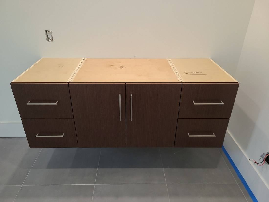 A dark wood flat-panel vanity with two doors and four drawers, fixed to the wall clear of the tile floor
