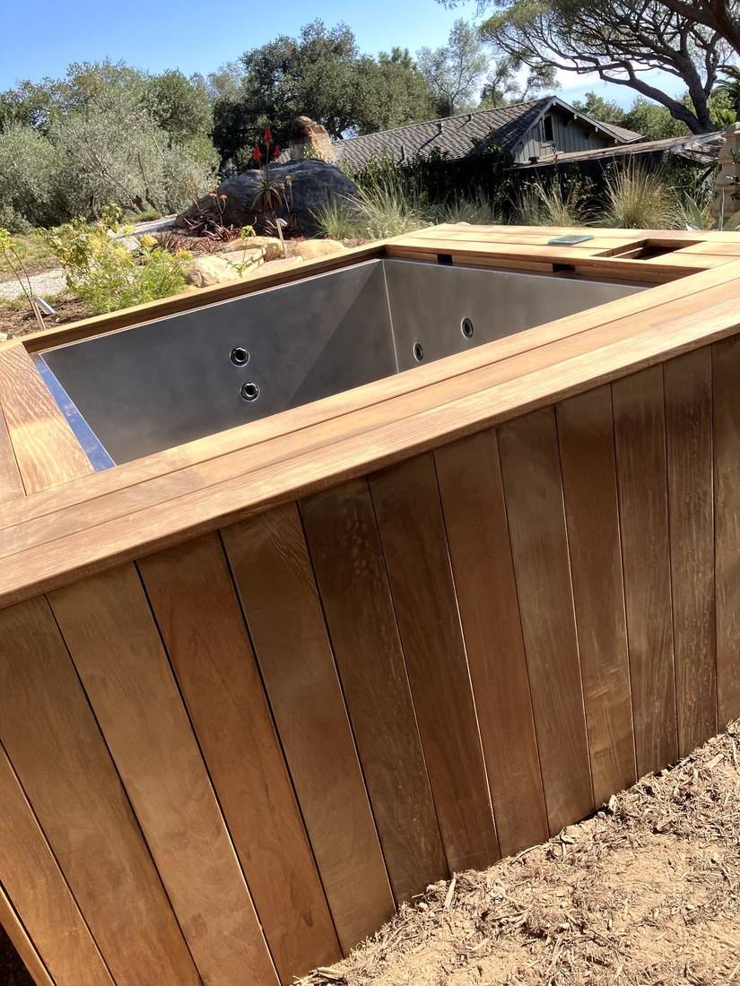 Close view of vertical hardwood cladding and the hardwood cap around a stainless steel spa