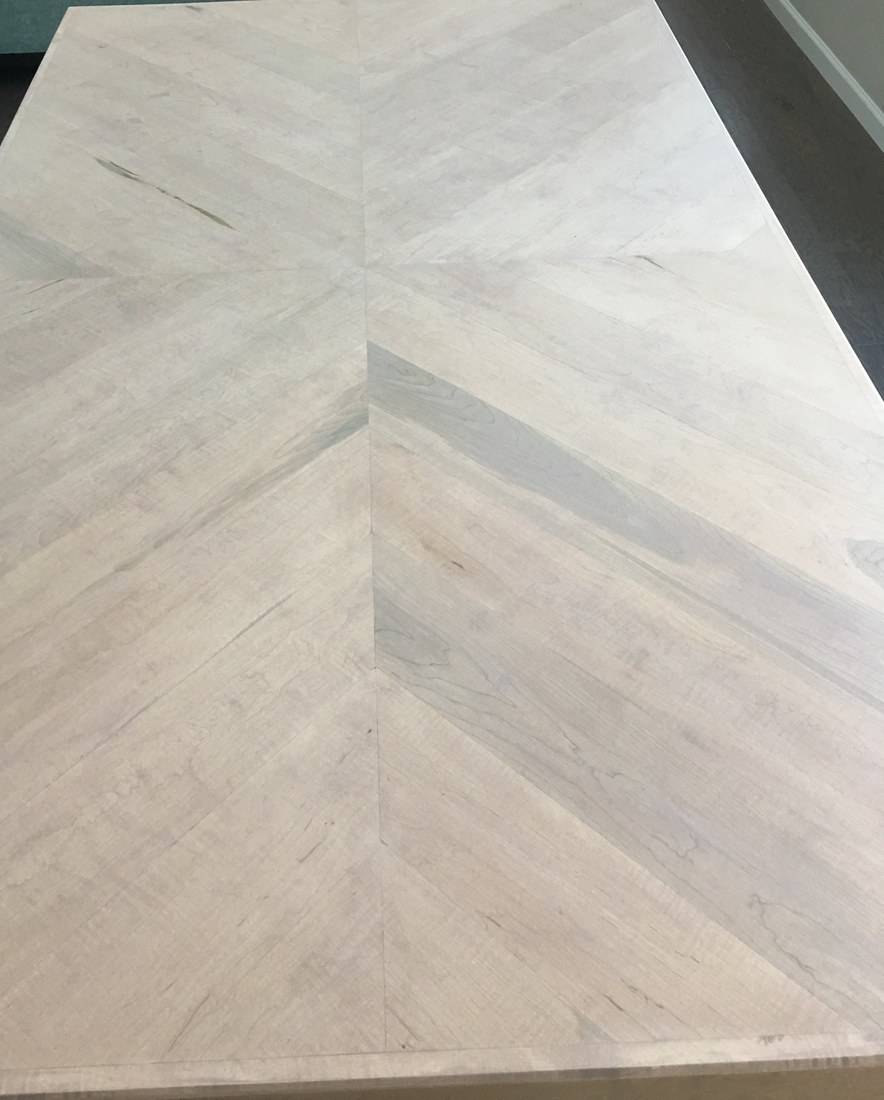 A maple tabletop with boards laid in a chevron pattern meeting along the center line