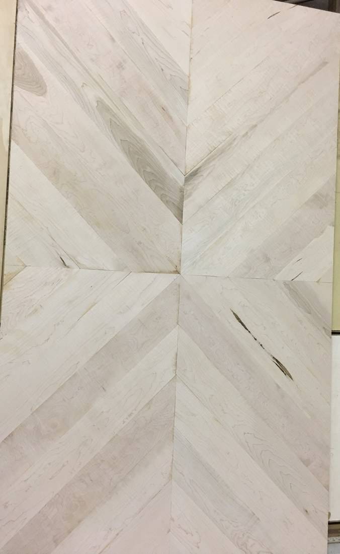 Maple boards laid out in a chevron pattern on a workbench