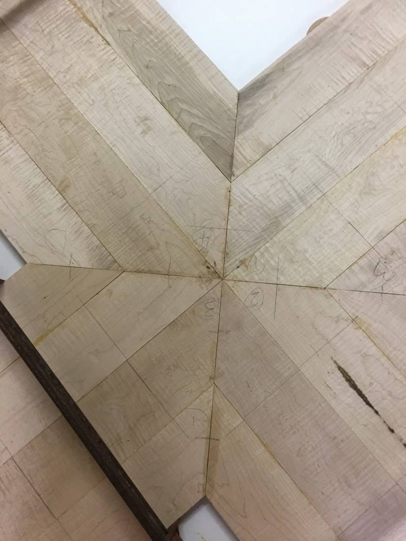 Angled maple boards meeting at a single center point, each numbered in pencil