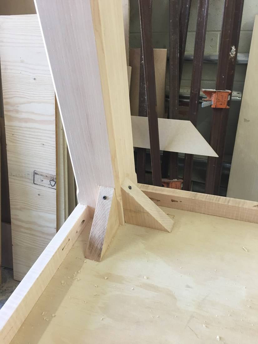 The underside of a table showing a leg fixed to the aprons with wooden corner blocks