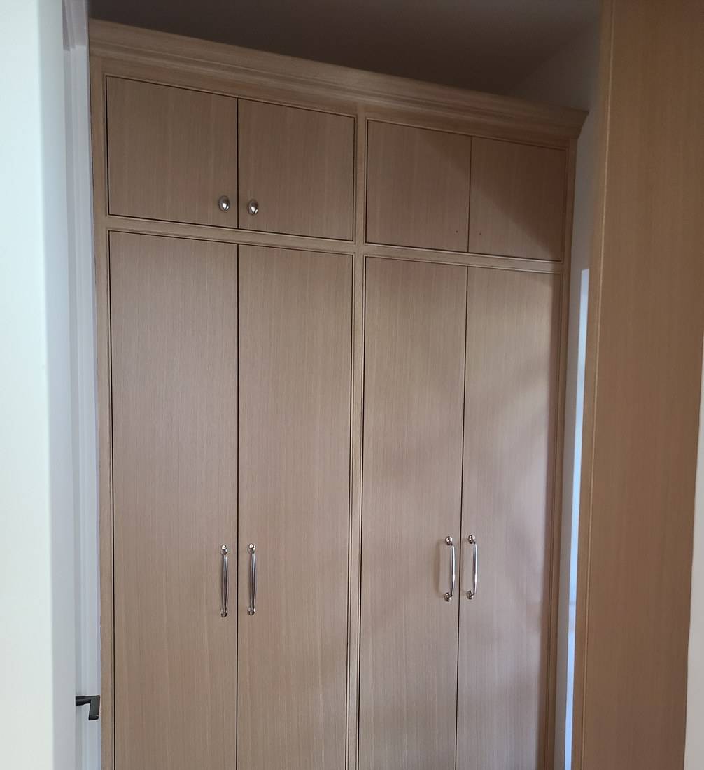 Tall pale oak cabinet doors with long pulls, built to the ceiling