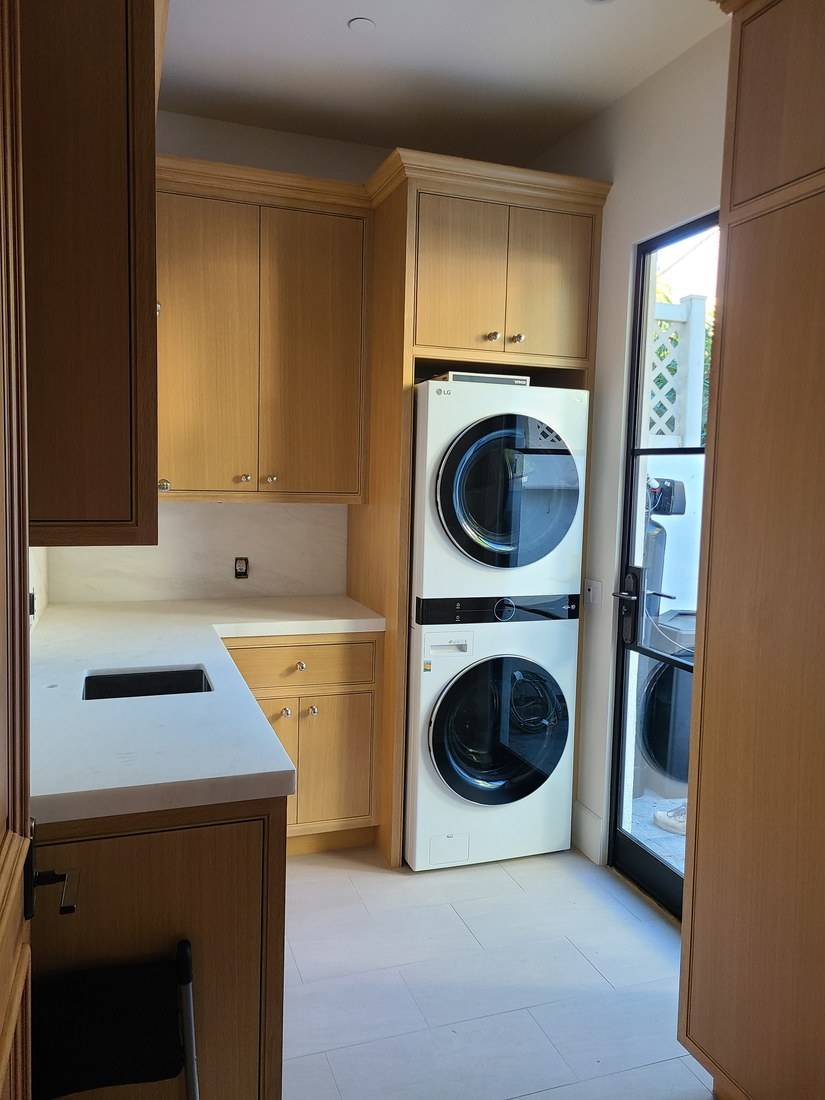 Pale oak laundry cabinets around a stacked washer and dryer