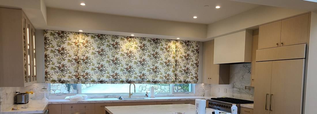 Pale oak flat-panel cabinets around a range and hood, with a refrigerator hidden behind matching oak panels